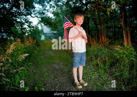 Young, patriotic boy holds up an American flag; Lincoln, Nebraska, United States of America Stock Photo
