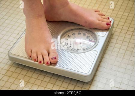 Young woman's feet standing on a scale in the bathroom; Lincoln, Nebraska, United States of America Stock Photo