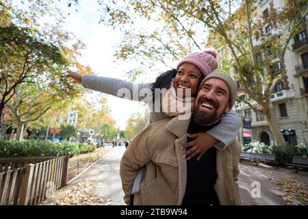 Portrait of young cheerful multiracial happy couple in love hugging and smiling in piggyback Stock Photo