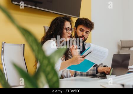 A couple of colleagues collaborate in a modern co-working space, sharing ideas and discussing strategy for profit growth and successful projects. Stock Photo