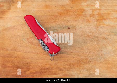 Red pocket knife and multi-tool on a wood board Stock Photo