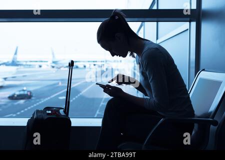 Young woman traveler at airport using her smartphone. Stock Photo