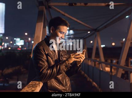 Happy young man using smartphone in the city, technology, social media lifestyle Stock Photo