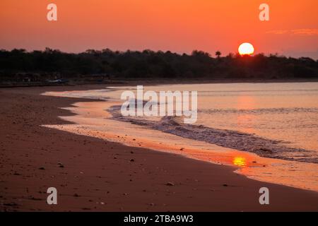 The sun drops behind a sandy beach near Baucau on the northeast coast of The Democratic Republic of Timor-Leste. Stock Photo