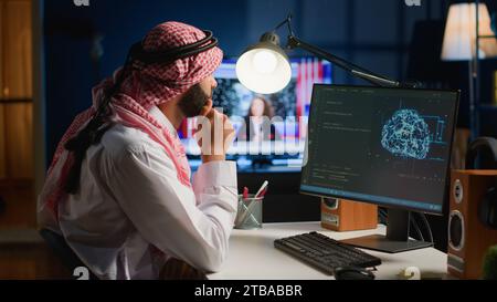 Computer operator updating artificial intelligence neural networks, writing complex binary code scripts. Outsourcing arabic freelancer in personal office uses digital device programming to upgrade AI Stock Photo