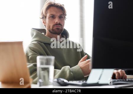 Front view portrait of bearded software programmer looking at computer screen with focused face expression while working in office Stock Photo