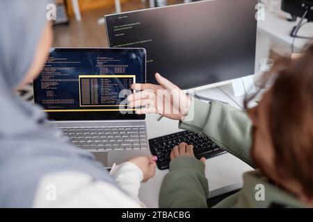 High angle closeup of two colleagues reviewing code in IT development office and pointing at computer screen Stock Photo