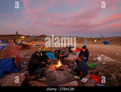 Jacumba Hot Springs, California, USA. 3rd Dec, 2023. Asylum seeking migrants from China try to stay warm next to a fire in an open-air holding area next to the U.S.-Mexico border near the small, desert San Diego County community of Jacumba Hot Springs. The U.S. is seeing a big increase in Chinese immigrants arriving using a relatively new and perilous route through Panama's Darien Gap jungle, thanks in part to social media posts and videos providing step-by-step guidance. (Credit Image: © K.C. Alfred/ZUMA Press Wire) EDITORIAL USAGE ONLY! Not for Commercial USAGE! Stock Photo