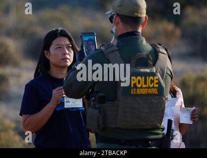 Jacumba Hot Springs, California, USA. 3rd Dec, 2023. A female asylum seeking migrant from China holds up her passport and paperwork as she is photographed by a U.S. Border Patrol agent in an open-air holding area as they prepare to board a bus to a processing facility near to the small, desert San Diego County border community of Jacumba Hot Springs. The U.S. is seeing a big increase in Chinese immigrants arriving using a relatively new and perilous route through Panama's Darien Gap jungle, thanks in part to social media posts and videos providing step-by-step guidance. (Credit Image: © K.C Stock Photo