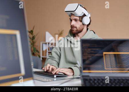 Side view portrait of bearded IT developer wearing VR headset working on immersive technology in office Stock Photo