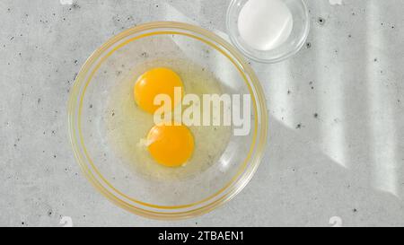 Raw eggs in a glass bowl, and salt in a glass bowl close-up on a light grey background, copy space Stock Photo