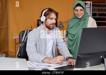 Portrait of bearded young man discussing project ideas with smiling female colleague in office Stock Photo