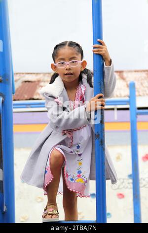 Indigenous 4 year old girl with traditional dress and huaraches plays in street games living in poverty Stock Photo