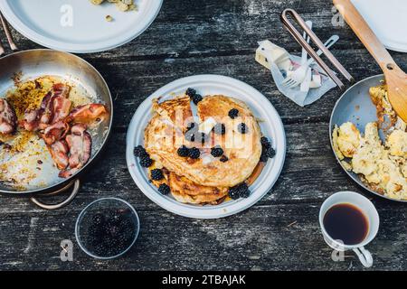 high angle view of American breakfast camping tabletop with pancakes, bacon, scrambled eggs, coffee Stock Photo