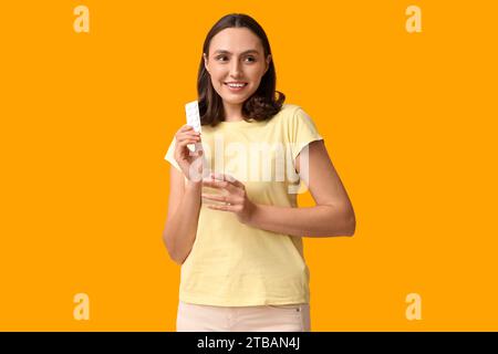 Beautiful young woman with pills and glass of water on yellow background Stock Photo