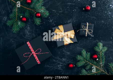 Gift boxes, Christmas balls and fir tree on black background with snow. Winter holidays concept. Top view, flat lay. Stock Photo