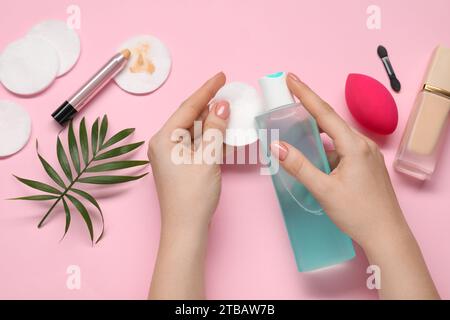 Woman with makeup remover, cotton pads, foundation, concealer and sponge on pink background, top view Stock Photo