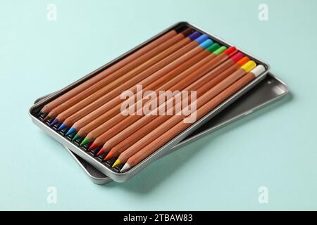 Box with many colorful pastel pencils on turquoise background. Drawing supplies Stock Photo