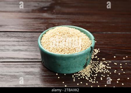 Dry quinoa seeds in bowl on wooden table Stock Photo