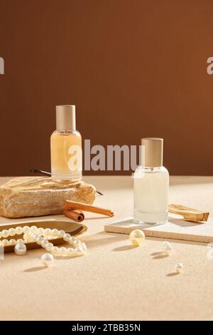 Front view of glass spray bottle unlabeled decorated on brown background with pearl necklace, cinnamon sticks and vanilla. Mockup scene for advertisin Stock Photo