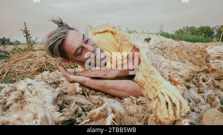 funny adult farmer taking sleep a nap on sheep wool mulch ready for planting cabbage in organic vegetable garden during summertime Stock Photo