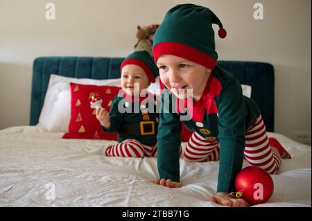 Baby girl and toddler dressed as elves having fun on a bed Stock Photo