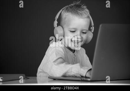 Cute boy wearing headphones, study with laptop in classroom, listening ...