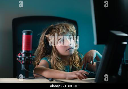 A little boy child uses a desktop at night, a child with computer screen in the room with neon lightning. Social network for kids Stock Photo