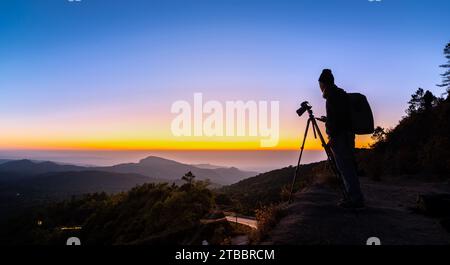 Silhouette Professional Photographer with camera take a landscape photo at twilight sunrise Stock Photo