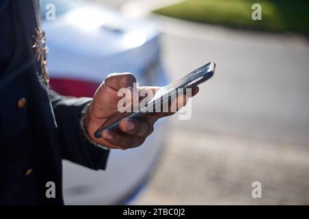 Cropped image of Black business man holding cellphone while outside Stock Photo