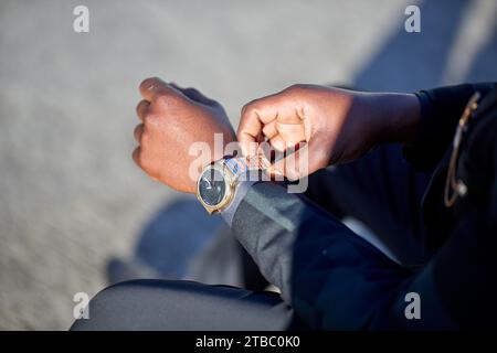 Cropped image of Black man in formal wear putting on his watch Stock Photo