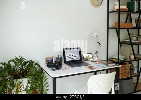 Laptop, digital camera and printed photos on desk of photographer Stock Photo