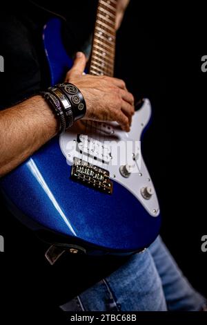 musician in jeans and blue electric guitar in acoustic concert with black background Stock Photo