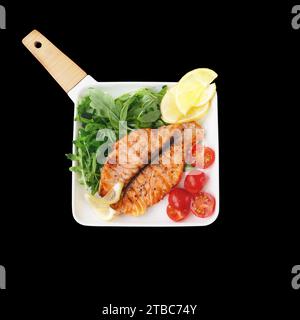 Grilled salmon Butterfly steak with cherry tomatoes and arugula salad on a white square plate. Close-up. Top view, flat, isolated on black. Stock Photo