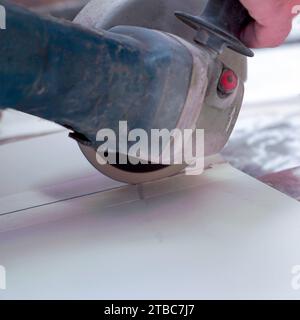 A construction worker saws ceramic tiles using an angle grinder Stock Photo