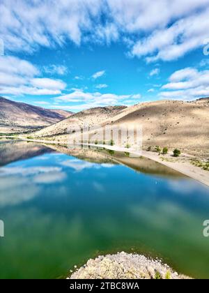 A bird's eye view of a lake surrounded by mountain peaks in the background Stock Photo