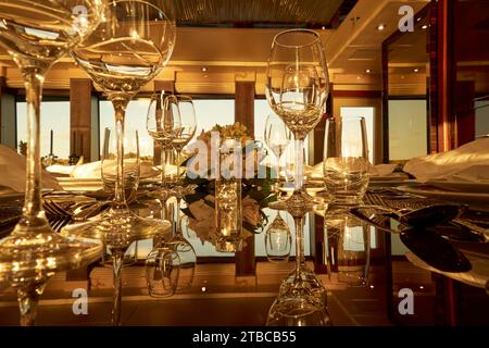 Luxury yacht charter table setting with flowers,wine glasses and marine decorations. Stock Photo