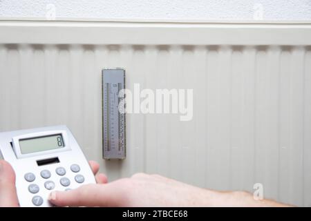 Close up view of a man using a calculator on a heating radiator Stock Photo