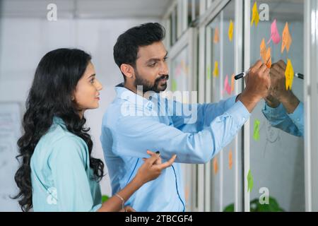 Two colleagues or young businesspeople at office planning or solving corporate problem by discussing - concept of brainstorming ideas, teamwork and Stock Photo