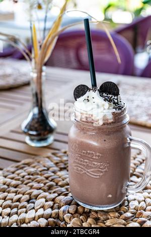 an image of a chocolate smoothie milkshake topped with cookies on a restaurant table. Stock Photo