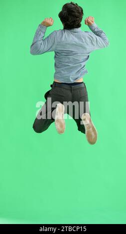man in full growth. isolated on green background jumping rejoices Stock Photo