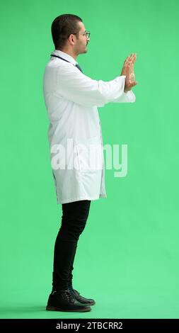 male doctor in a white coat on a green background shows a cancel sign Stock Photo