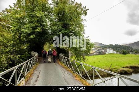 Walkers crossing a bridge over Goldrill Beck, Patterdale, Lake District, Cumbria Stock Photo
