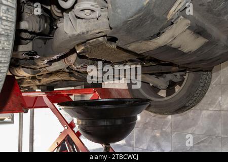 Changing old motor oil in automobile repair service. maintenance and checkup in car workshop. Auto is on hydraulic lift in garage workshop Stock Photo