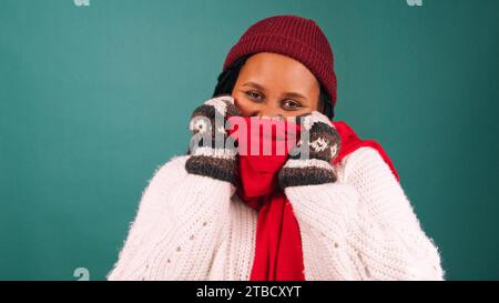 Freezing cold woman bundles up against the cold, huddles in warm scarf, studio Stock Photo