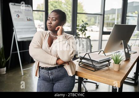 Thoughtful curvy woman standing in front of wall Stock Photo - Alamy