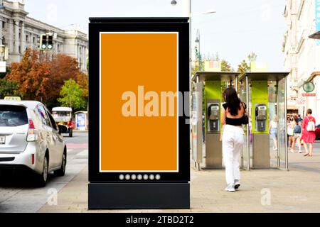blank street ad panel and lightbox with pedestrians walking by. commercial sign and base for advertising mockup. vertical glass digital poster Stock Photo