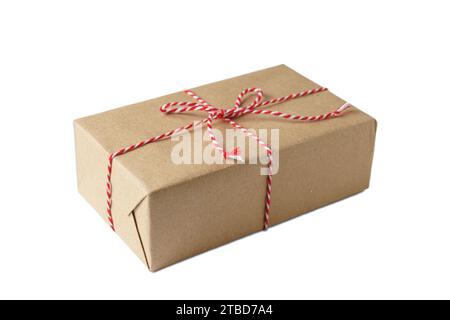 Christmas and New Year gift box wrapped in brown craft kraft paper with red and white baker's twine, ribbon bow isolated on white background Stock Photo