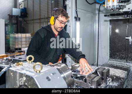 Manual worker with protective goggles and headphones using a milling cnc modern machine Stock Photo