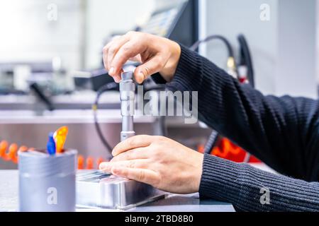 Close-up of an unrecognizable manual worker using tool to fix a metal piece in a cnc modern factory Stock Photo